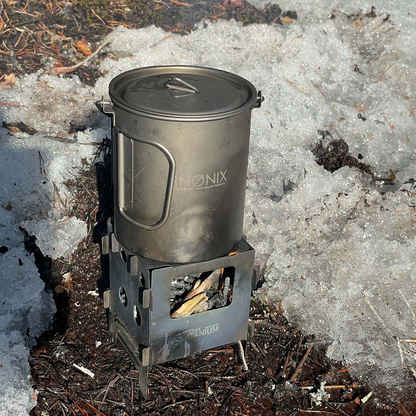 En 700 ml titan turkjele plassert på en kvistbrenner i snødekt terreng, klar for å koke vann over bål.