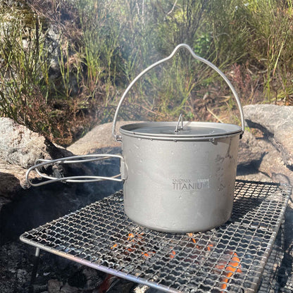 Titan turkjele på 1500 ml plassert over et bål på en rist, omgitt av natur og røyk fra bålet.