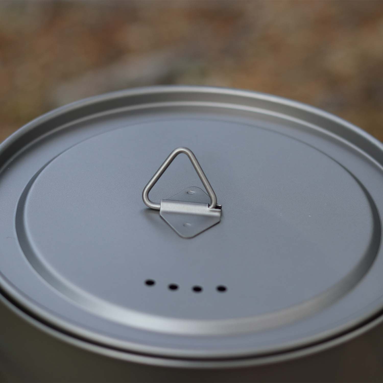 Nærbilde av lokket på en titan turkjele, med en robust trekkring og ventilasjonshull for dampflukt.